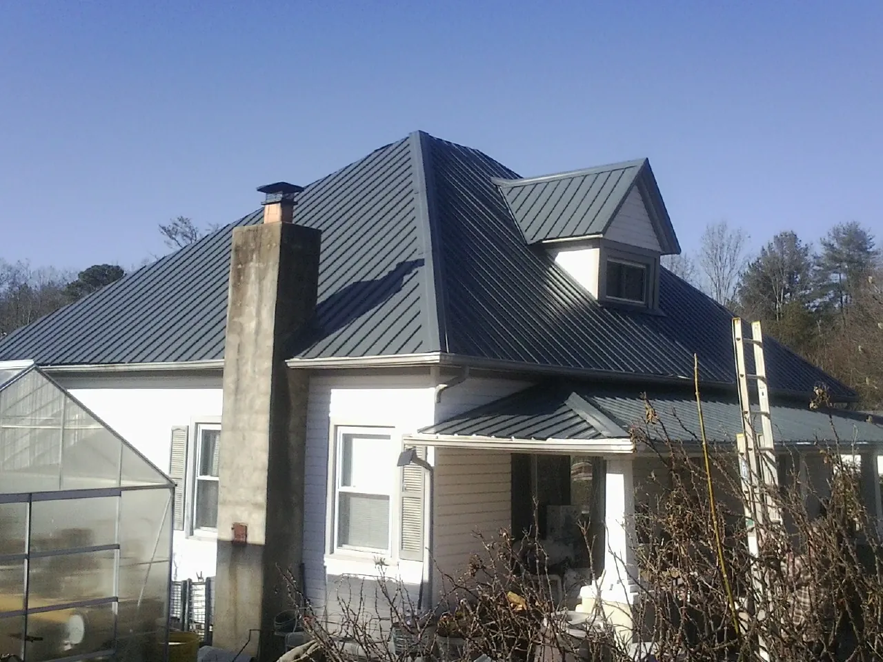 Dark blue standing seam metal roof on a white farmhouse with dormer — Slate & Tile Roof Repair by Roofing Brothers in Morris Plains