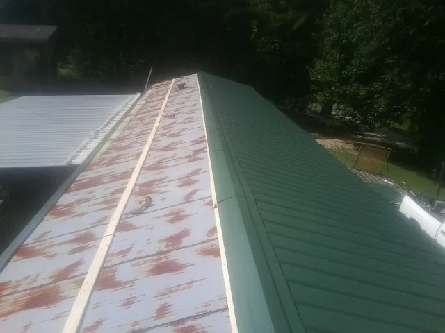 Old rusted panels beside newly installed green metal roofing — Wind Damage Roof Repair by Roofing Brothers in Morris Plains