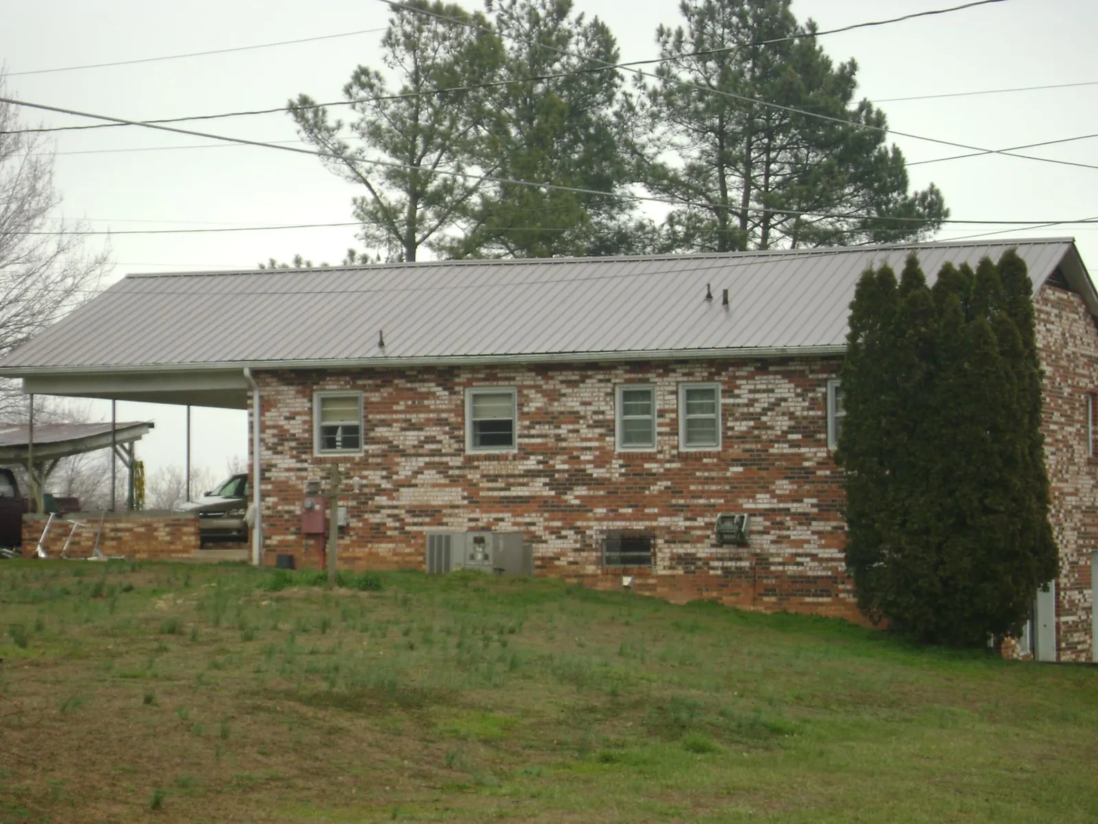 Gray metal roof on a brick split level home with a carport in Morris Plains