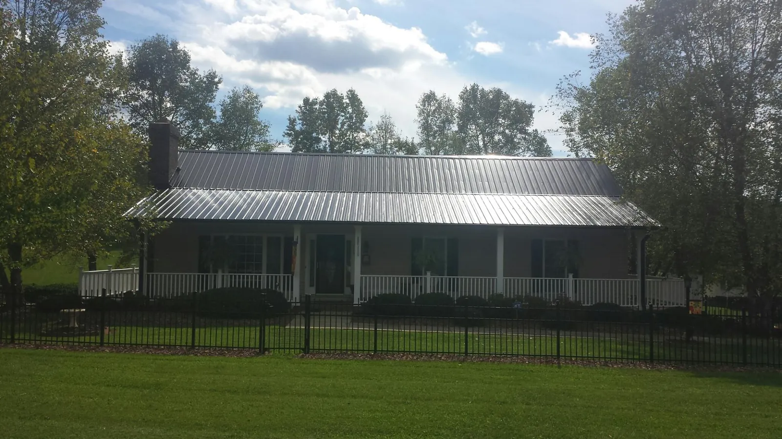Gray metal roof on a brick ranch with a full width front porch — Gutter Guard Installation work by our crew in Morris Plains