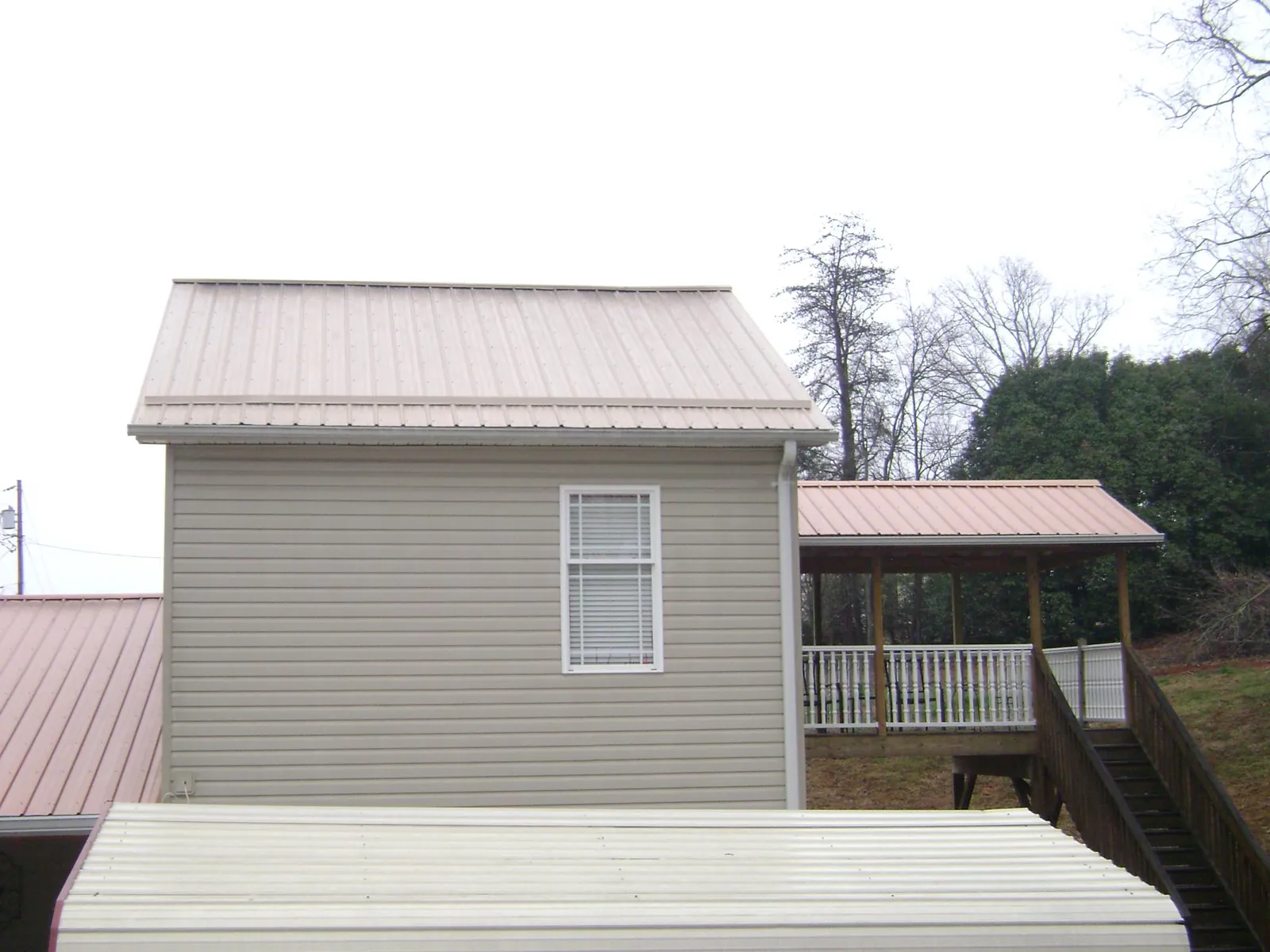 Tan metal roofs on a two story addition and attached porch, from a Roof Replacement job in Morris Plains