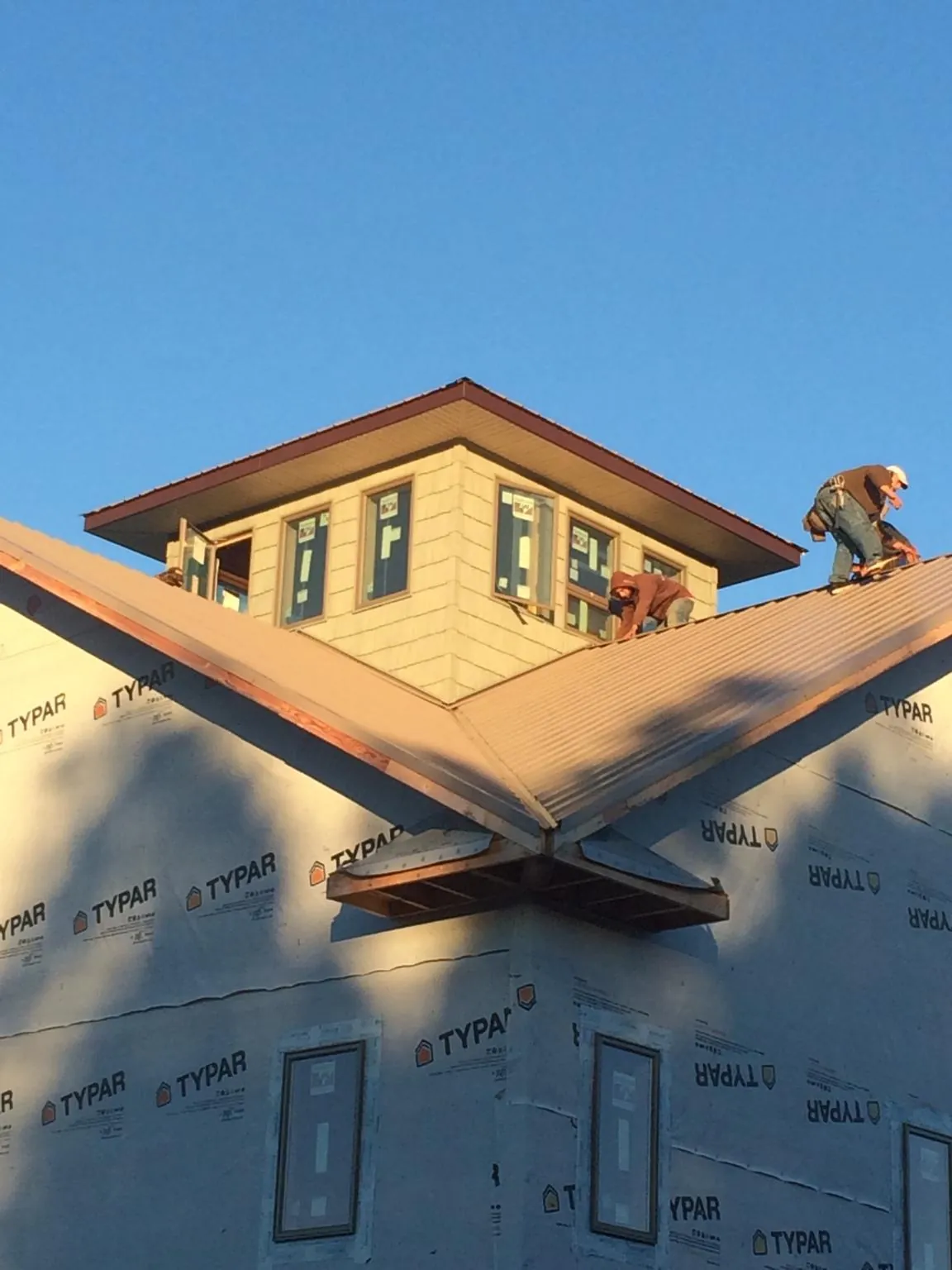 Roofers working around a rooftop cupola on a new metal roof at sunset — Roof Waterproofing in Morris Plains by Roofing Brothers